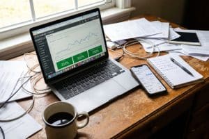 Laptop cu dashboard Google Ads și telefon cu statistici de campanie, ilustrând ce înseamnă ROI în marketing digital